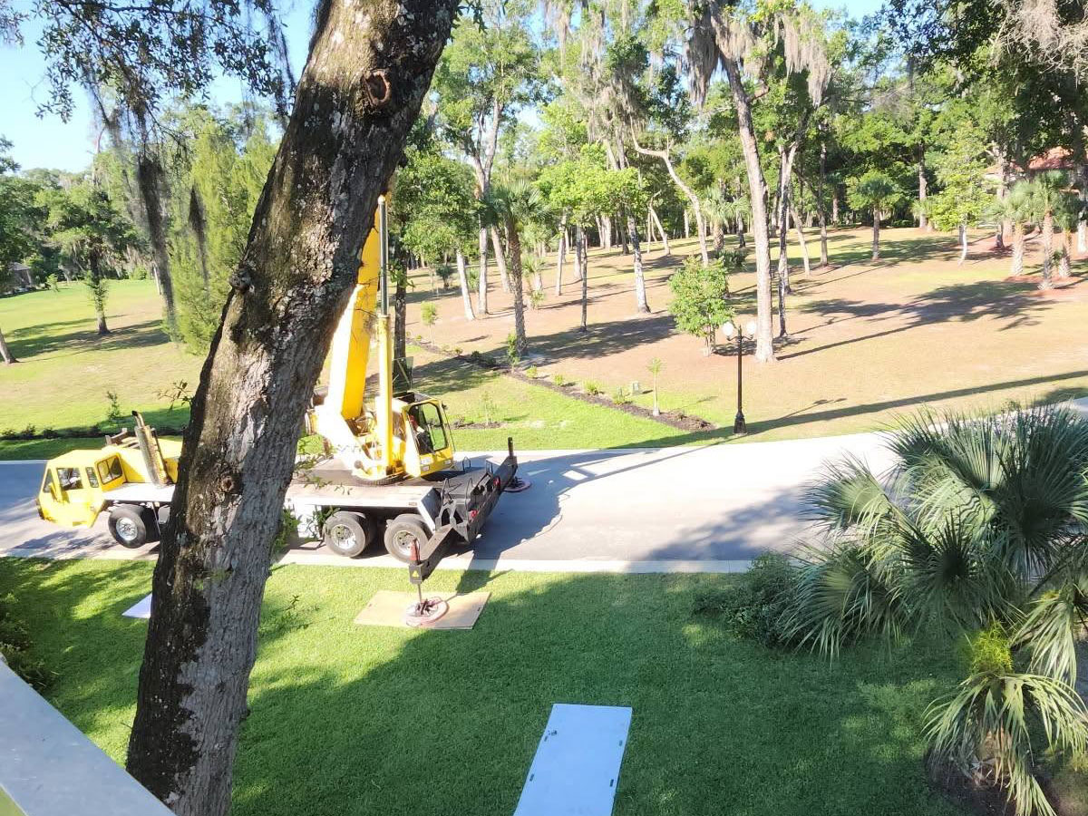Tree removal crane positioned beside a manicured lawn with protective ground mats in DeLand, Florida